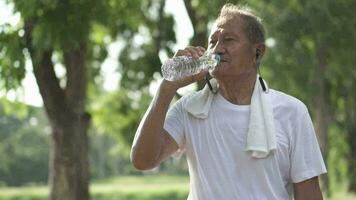 Sénior homme en buvant l'eau après exercice à le parc video