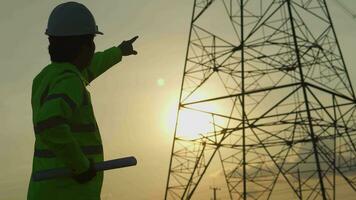 Engenharia dentro padrão segurança uniforme trabalhando inspecionar a eletricidade Alto Voltagem pólo com tábua perto torre com eletricidade. video