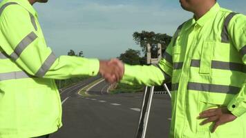 sondaggio ingegneri stretta di mano su strada costruzione luogo, dopo uso teodolite marchio un' autostrada a autostrada successo, civile ingegneri, perito attrezzatura. lavoro di squadra di perito ingegneri concetto. video