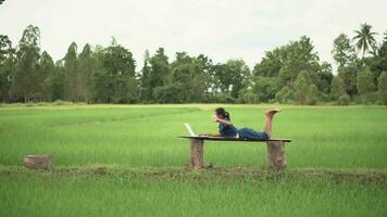 Asian girl live streaming on smartphone or laptop in rice field, countryside of Thailand. video