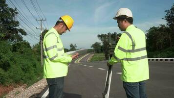 travail en équipe de arpenteur ingénieurs ouvrier fabrication mesure avec théodolite sur route Autoroute. enquête ingénieur à route construction placer, arpenteur équipement. construction concept. video