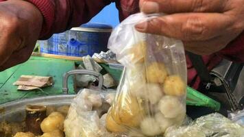 siomay vendedores servir compradores dentro plástico containers. siomay é uma típica indonésio lanche fez a partir de uma mistura do trigo farinha e peixe ou frango carne combinado com amendoim molho. video