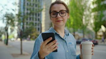 Caucasian woman in glasses walking around the city and using smartphone video