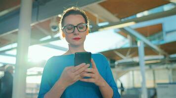 Woman stands at a transport stop and using smartphone. Slow motion video