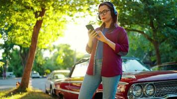 vrouw is staand buitenshuis in de buurt de rood wijnoogst auto en gebruik makend van smartphone video