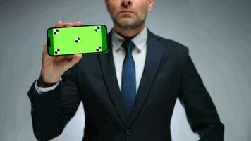 Man shows smartphone with green screen chroma key smartphone on camera. video