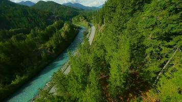 FPV drone flight over the road and the fast moving river with rapids. video