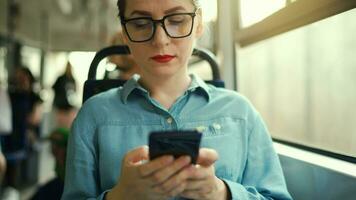 pubblico trasporto. donna nel bicchieri nel tram utilizzando smartphone. lento movimento video