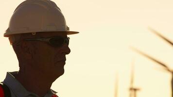 silhouet van een ingenieur met wit helm in wind boerderij video