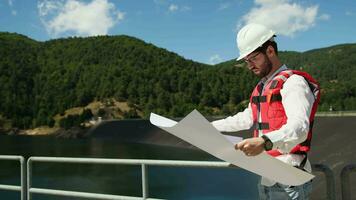 Engineer with white helmet holds a project of the new dam video