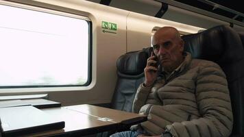 Old businessman making a work call while traveling on an high speed train video