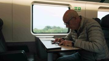 velho homem com óculos olhando às dele telefone enquanto viajando em uma trem video