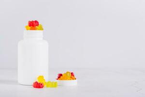 Bottle with gummy vitamin supplements in the shape of bears on the table photo