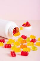 Chewable vitamin supplements spilled from a bottle on a pink background vertical view photo