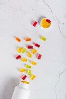 Bottle with gummy vitamin supplements in the shape of bears on the table top and vertical view photo