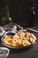 Pan-fried dumplings with soy sauce on a plate on the table vertical view photo