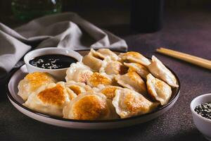 Pan-fried dumplings with soy sauce on a plate on the table photo