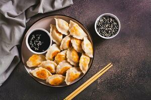 Pan-fried dumplings with soy sauce on a plate on the table top view photo