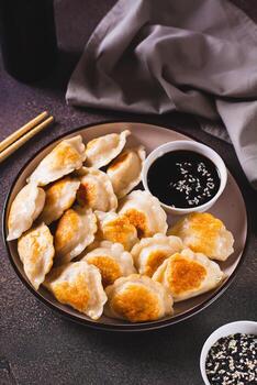 crujiente frito empanadillas con soja salsa y sésamo semillas en un plato vertical ver foto