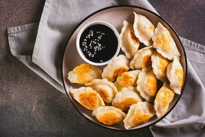 Close up of pan-fried dumplings with soy sauce on a plate on the table top view photo