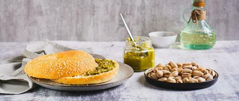 Bagel with pistachio cream butter and nuts for breakfast on a plate on the table web banner photo