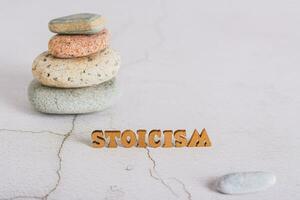 Concept of stoicism wooden letters on the background of a pyramid of stones on the table photo