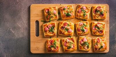 Snack mini pizza with sausages, tomato and cheese on a wooden board top view web banner photo