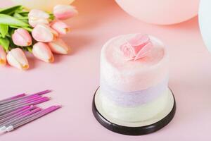 Cotton candy cake, flowers, candles and balloons for party on table photo