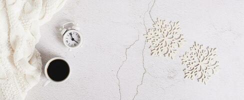 Winter web banner, coffee, alarm clock, sweater and snowflakes on light, top view photo