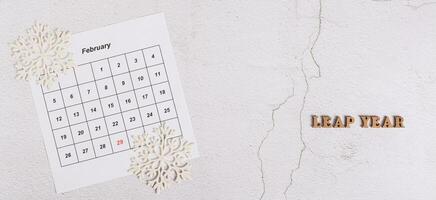 Leap year concept, calendar, snowflakes and text on light top view web banner photo