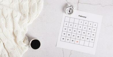 Leap year concept, calendar, alarm clock and coffee on light top view web banner photo