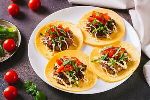 aplastar hamburguesa tacos con salsa, Tomates y albahaca en un plato en el mesa foto