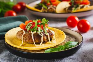 Smash Burger Tacos with beef patty, tomatoes and herbs on a plate photo