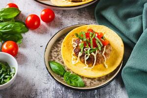 Smash Burger Tacos with beef patty, tomatoes and basil on a plate photo