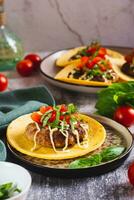 Smash Burger Tacos with beef patty, tomatoes and herbs on a plate vertical view photo