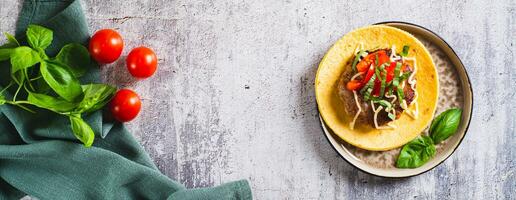 Smash Burger Tacos with beef patty, tomatoes and basil on a plate top view web banner photo