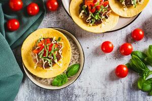 Smash Burger Tacos with beef patty, tomatoes and herbs on a plate top view photo