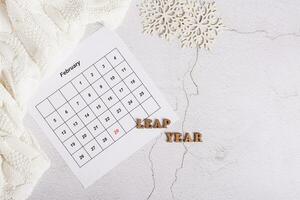 Leap year concept, calendar, sweater and snowflakes on a light background, top view photo