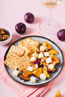Dinner for girls, biscuits, cheese, plums and walnuts on a plate on the table vertical view photo