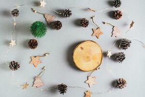 Christmas background, garland, pine cones, decorations and cut of a tree trunk on a gray photo