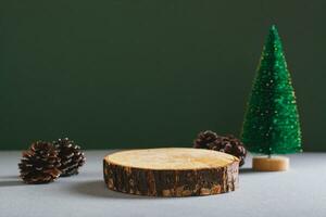 Podium made from a cut tree trunk, Christmas tree and pine cones on a green background photo