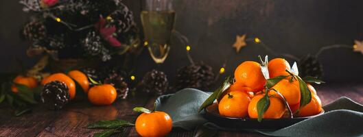 Whole tangerines with leaves on a plate on the table in Christmas decorations web banner photo