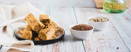 Sweet dessert halva from sunflower seeds with flax seeds on a plate web banner photo