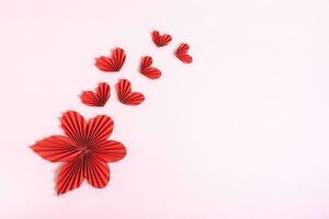 Beautiful composition of folded red paper hearts and leaves on a pink background copy space photo