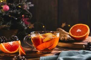 Fragrant tea with pieces of orange and ginger in a cup on the table photo