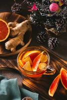 Delicious homemade tea with orange and ginger in a glass mug on the table vertical view photo
