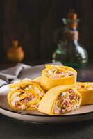 Tortilla rolls with salad of sausages, eggs, cheese and herbs on a plate vertical view photo