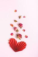 Folded red paper heart and dry flowers on a pink background vertical view photo