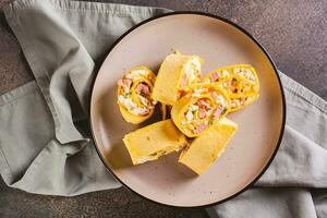 Tortilla rolls with salad of sausages, eggs, cheese and herbs on a plate top view photo