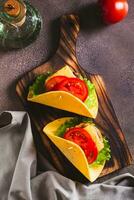 Taco burger in tortilla with cutlet, cheese and tomatoes on a board top and vertical view photo